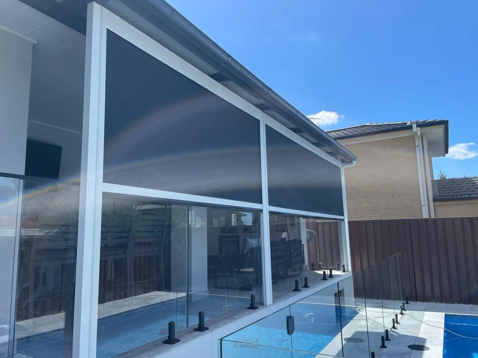Dark outdoor blinds installed beside a swimming pool